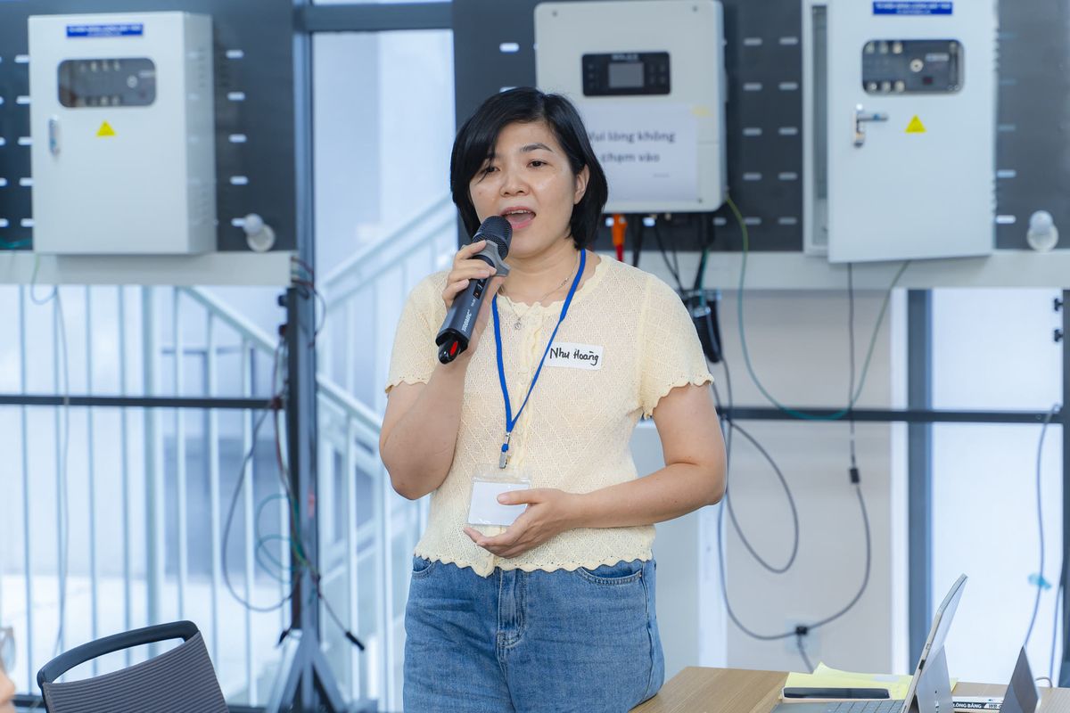 Một học viên nữ cầm micro chia sẻ trước lớp