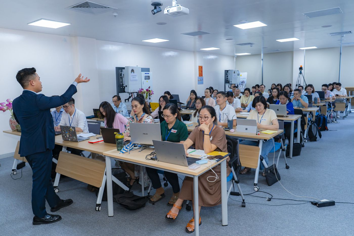 Toàn cảnh lớp học AI Agent ngày 28/9/2026: người hướng dẫn đứng giảng, học viên ngồi theo dãy bàn, mỗi người một laptop
